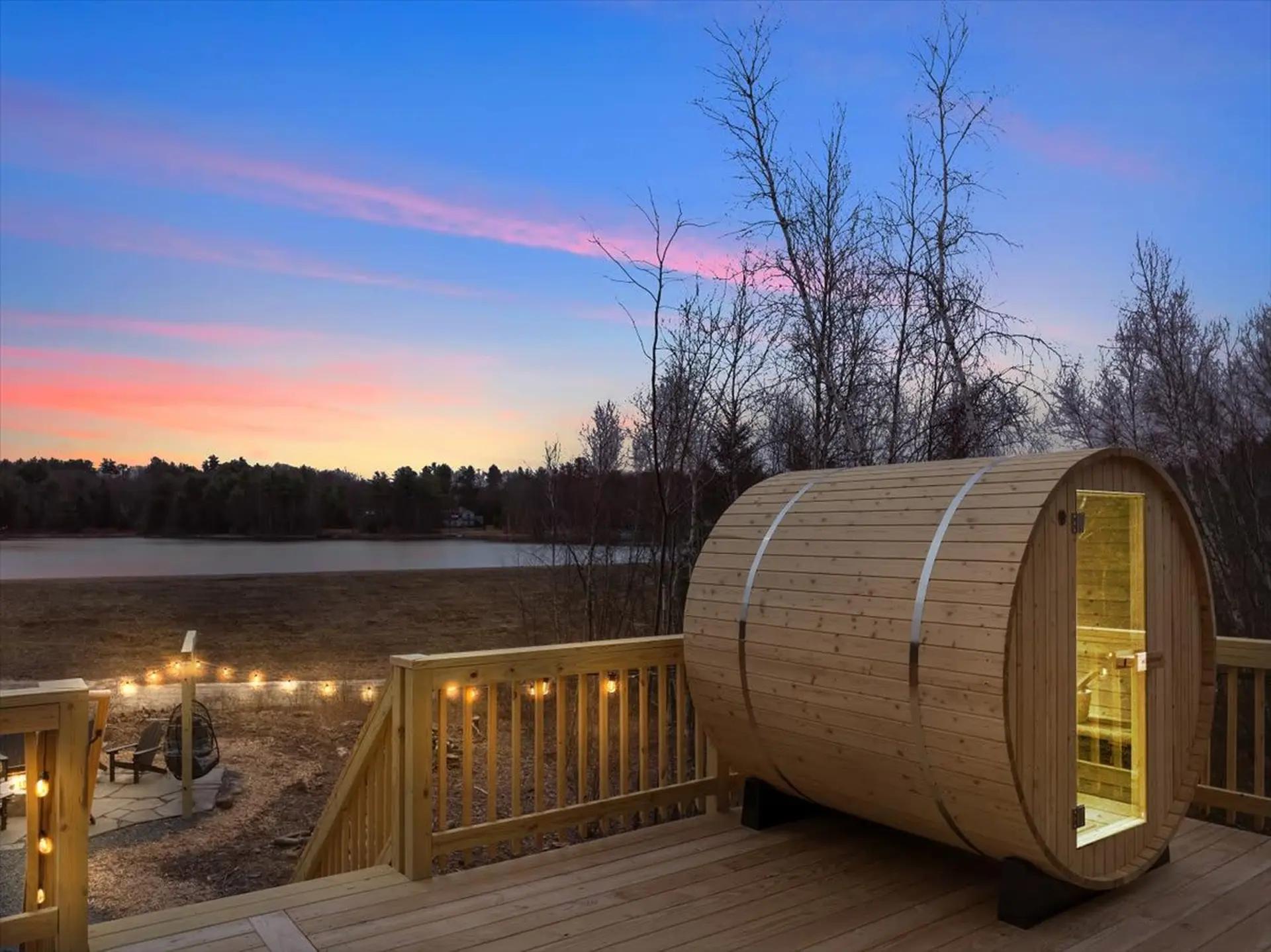 Outdoor barrel sauna on a wooden deck with sunset views at a mountain cabin